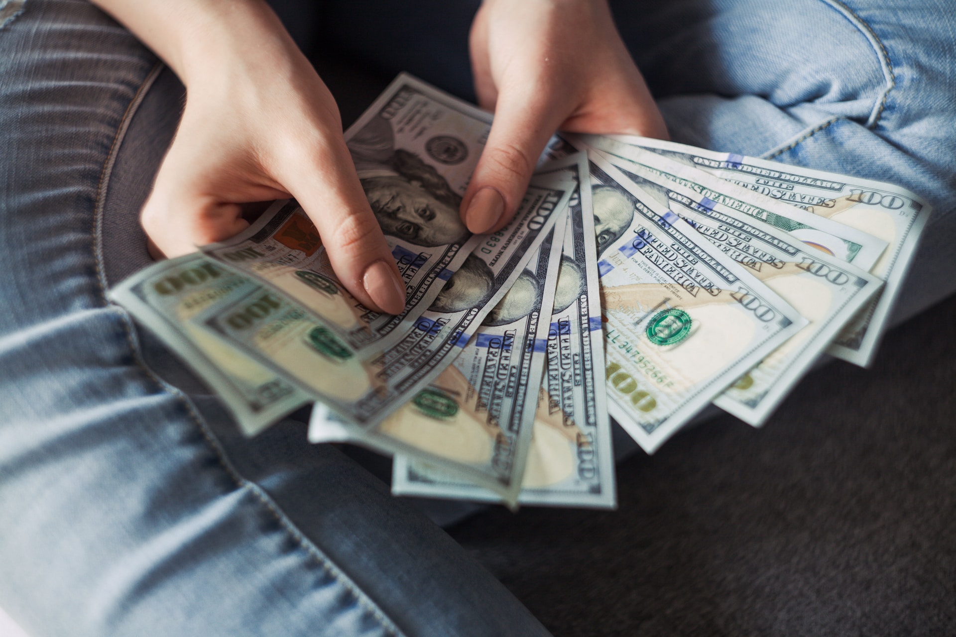 hands holding dollar bills in the shape of a hand fan